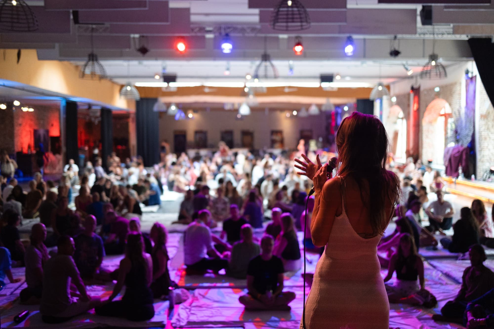 A crowd standing with their hands raised in the light at the close of an event