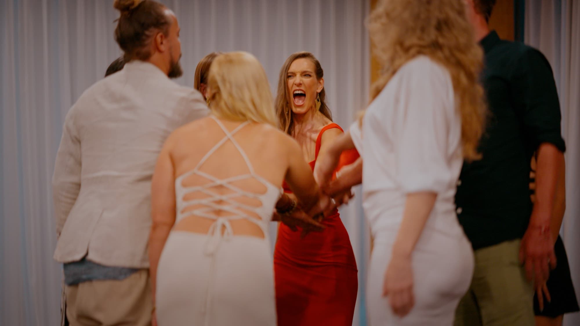 Arja Hendrikx in red among a standing crowd, mouth open mid shout, people moving around her